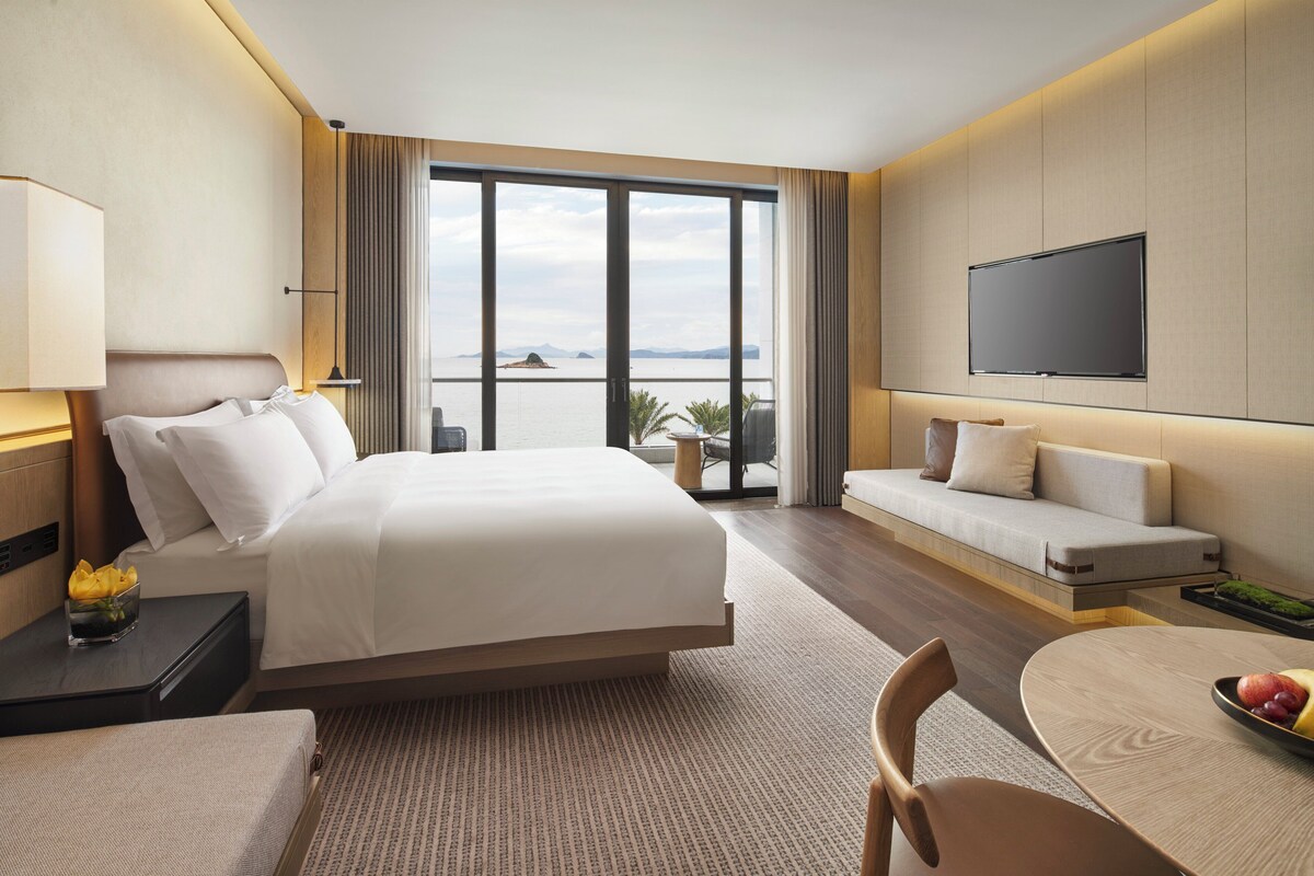 Una habitación de hotel con una cama grande, un sofá, una mesa de comedor y un televisor.
