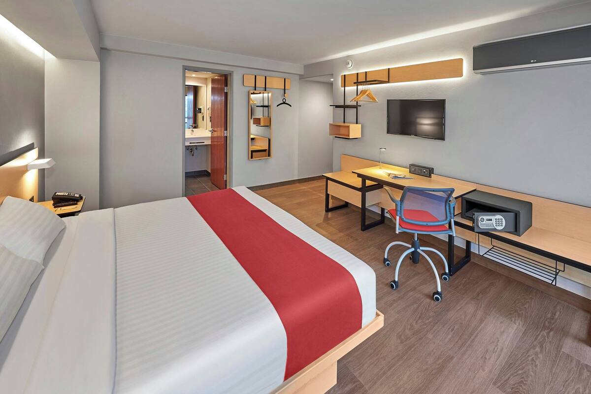 A modern hotel room with a large bed, a desk, and a chair.