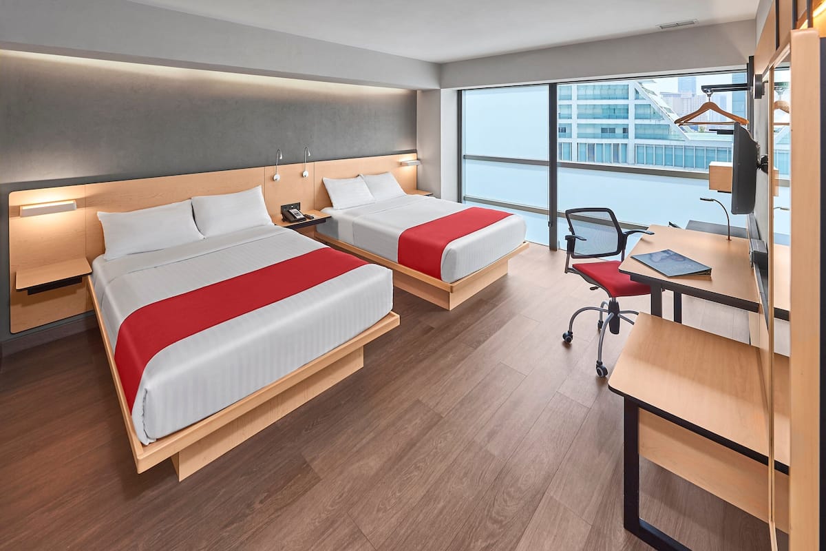 A modern hotel room with two beds, a desk, and a chair.