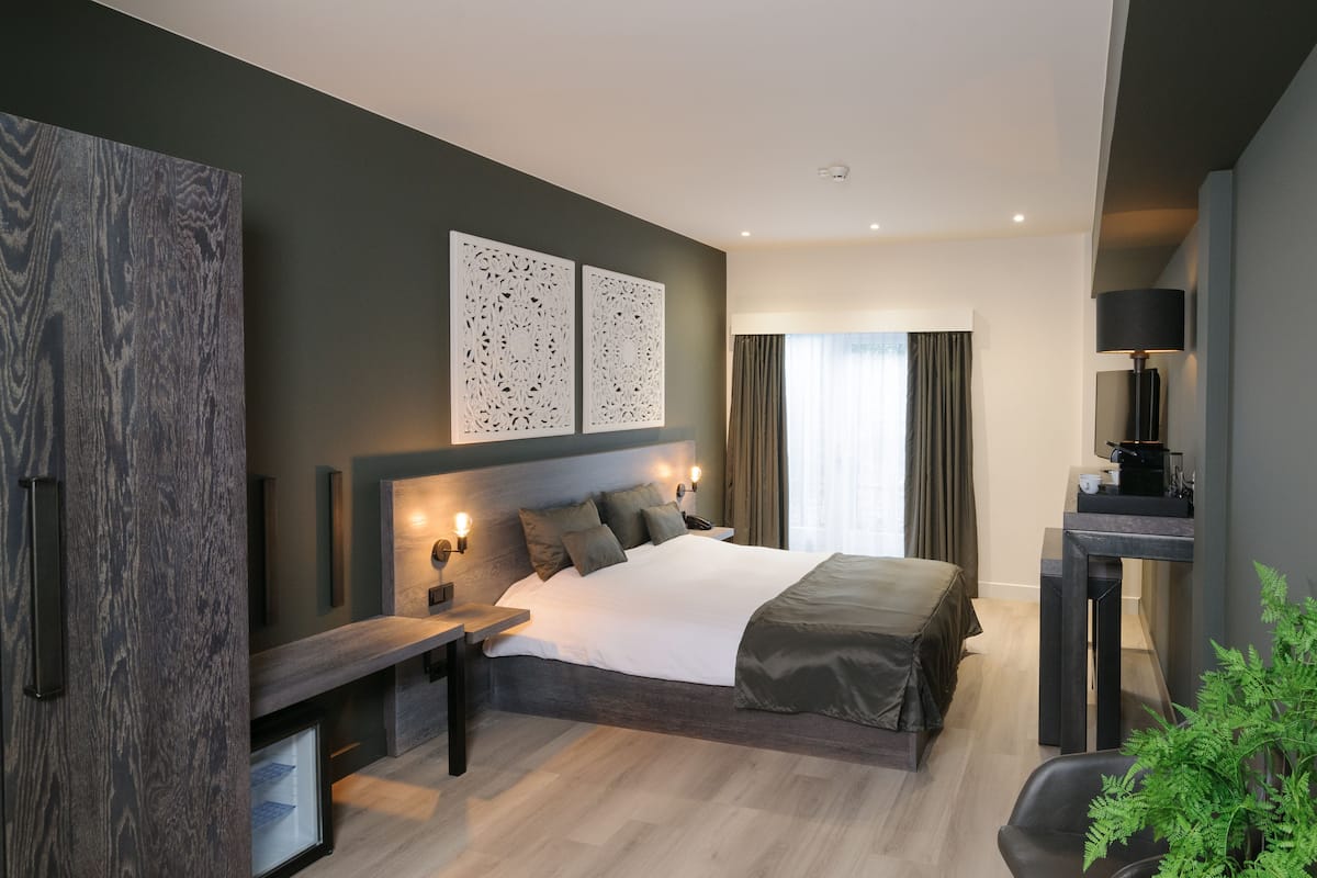 Ein modernes Schlafzimmer mit einem großen Bett, Nachttischen, einem Schreibtisch und einer Lampe.