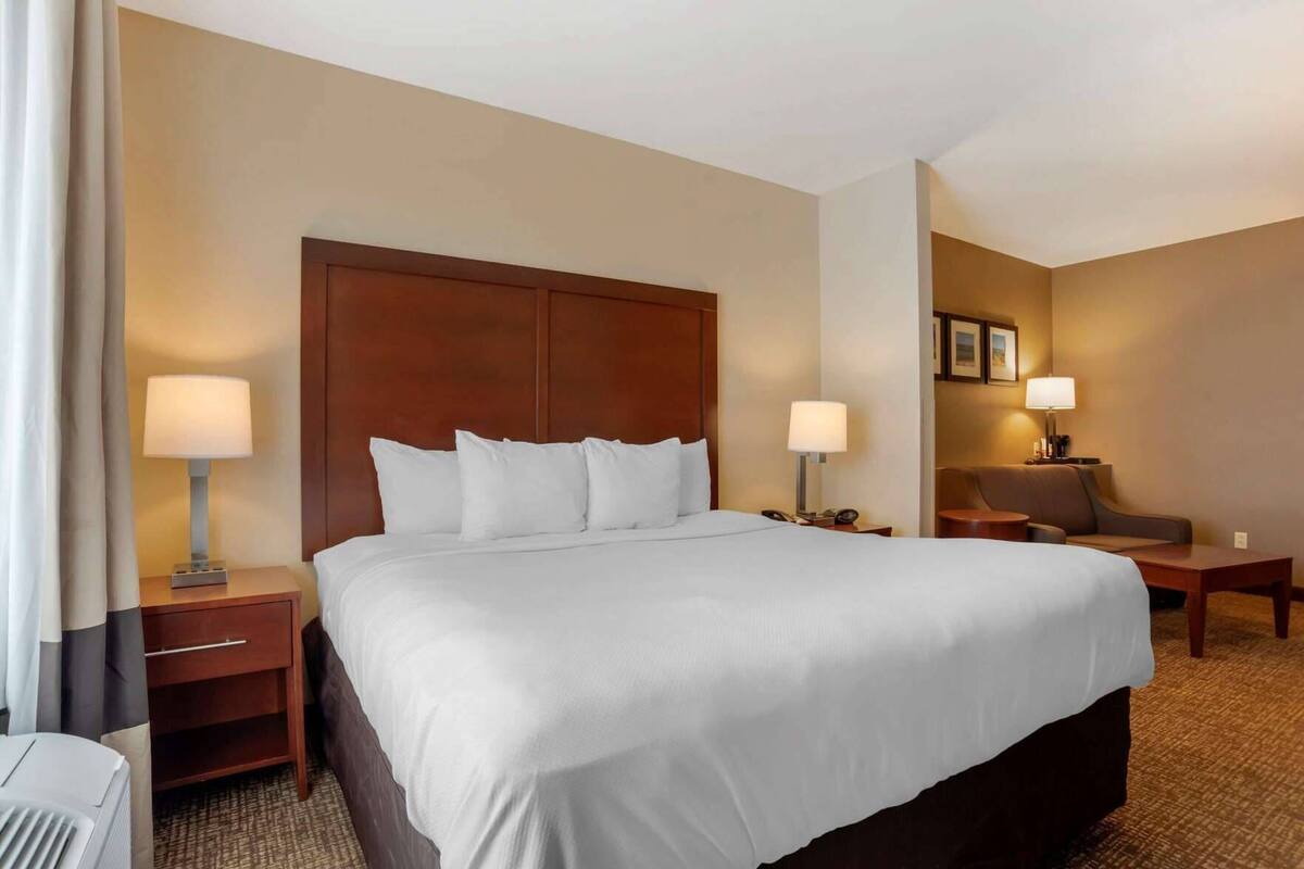 A hotel room with a large bed, two bedside tables, a chair, and a desk.
