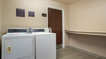A laundry area with two washing machines, a storage room, and a sign indicating guest laundry availability.