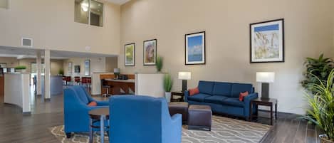 A spacious lobby with a blue sofa, armchairs, and a dining area in the background.