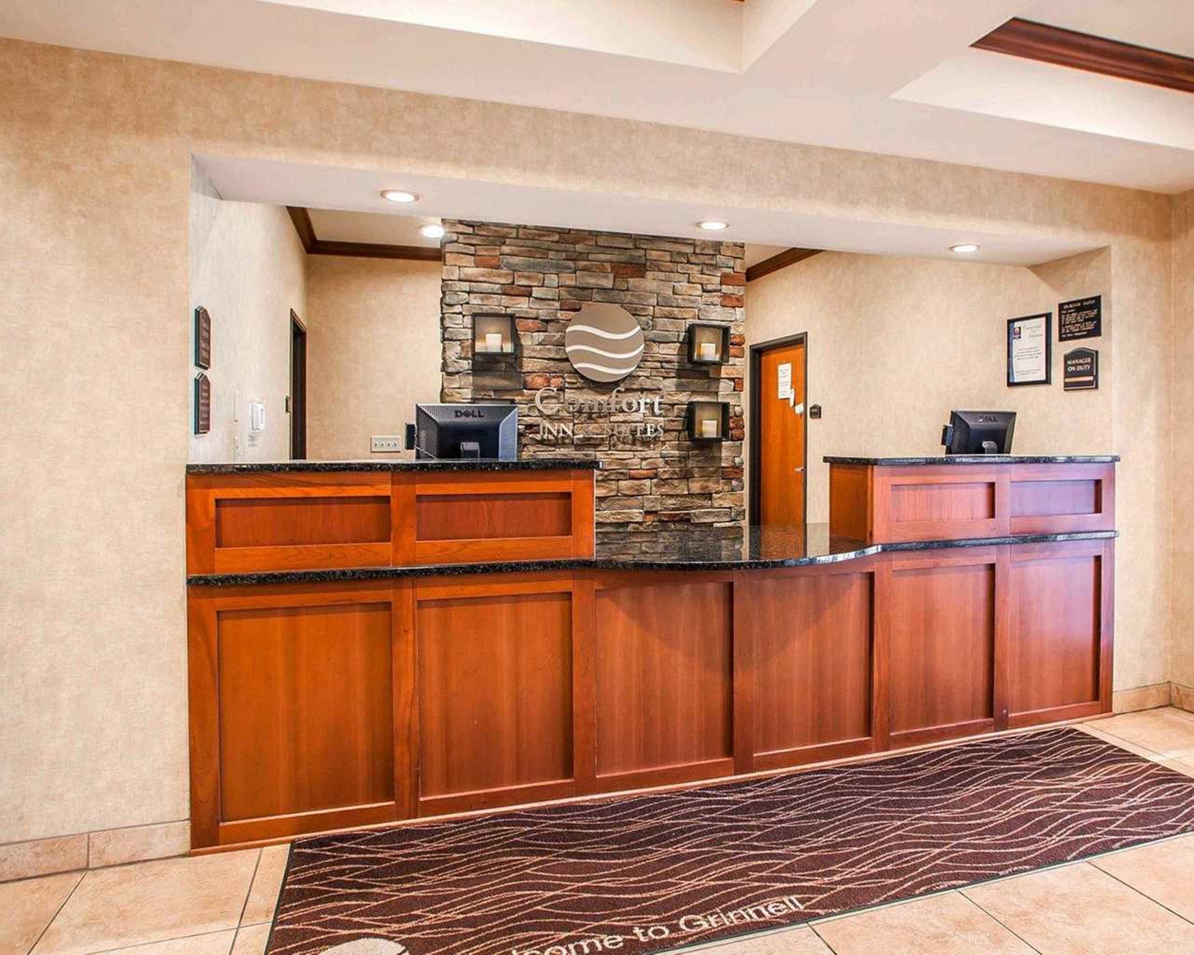 A hotel reception area with a stone wall, wooden reception desk, and a welcome mat.
