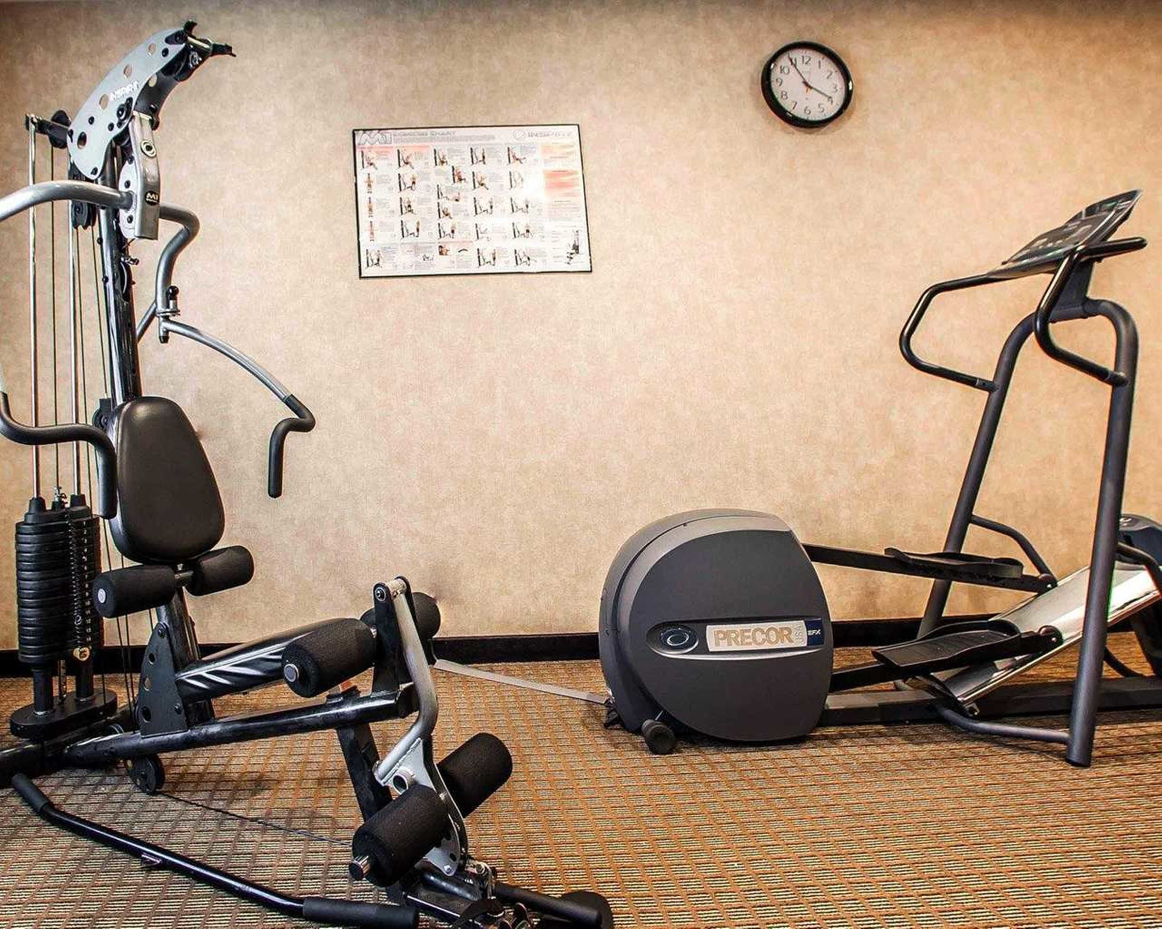 Un gimnasio con equipo de ejercicio que incluye una caminadora, elíptica y máquinas de pesas.