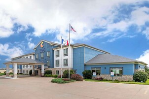 Un hotel con fachada azul, un acceso cubierto y banderas.