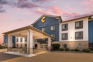 A Comfort Inn & Suites building with a covered entrance, stone facade, and a large C logo. - Comfort Inn & Suites Grinnell near I-80 (Grinnell)