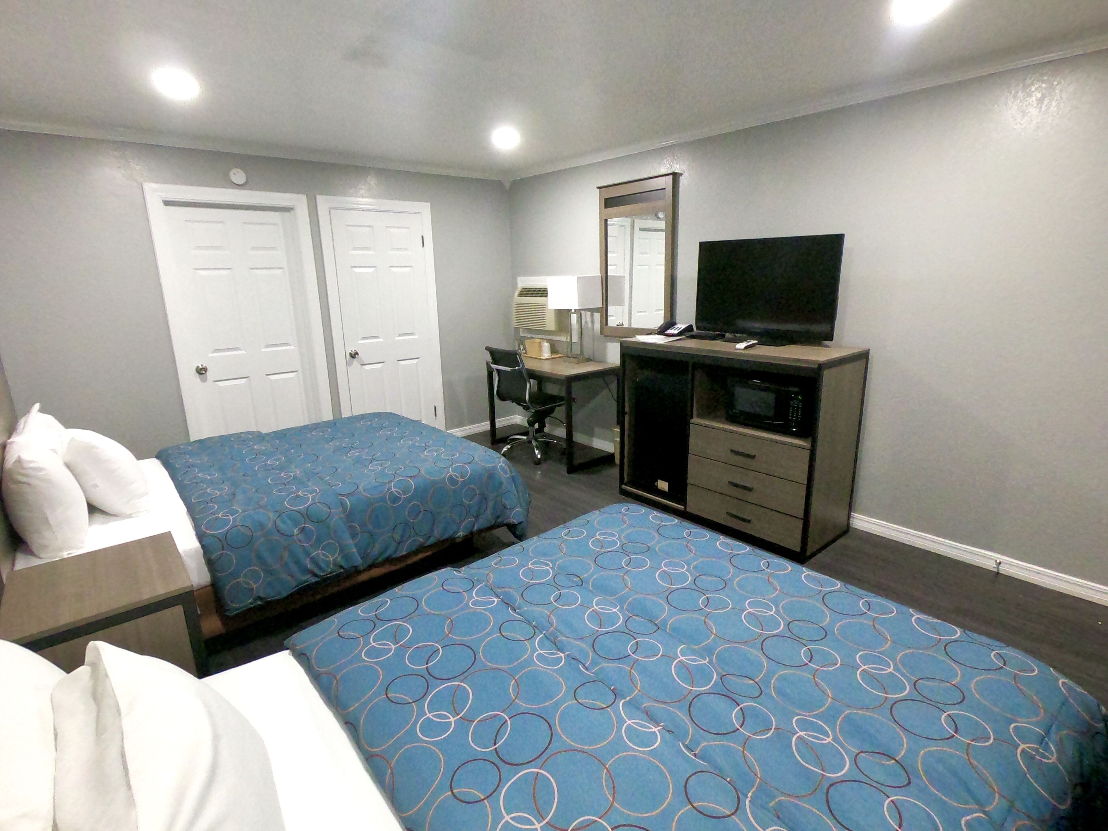 Una habitación de hotel con dos camas, un escritorio, un televisor y un microondas.