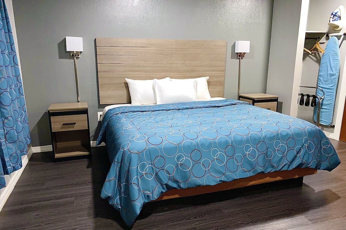 A hotel room with a bed, nightstands, a wardrobe, and a shower area.