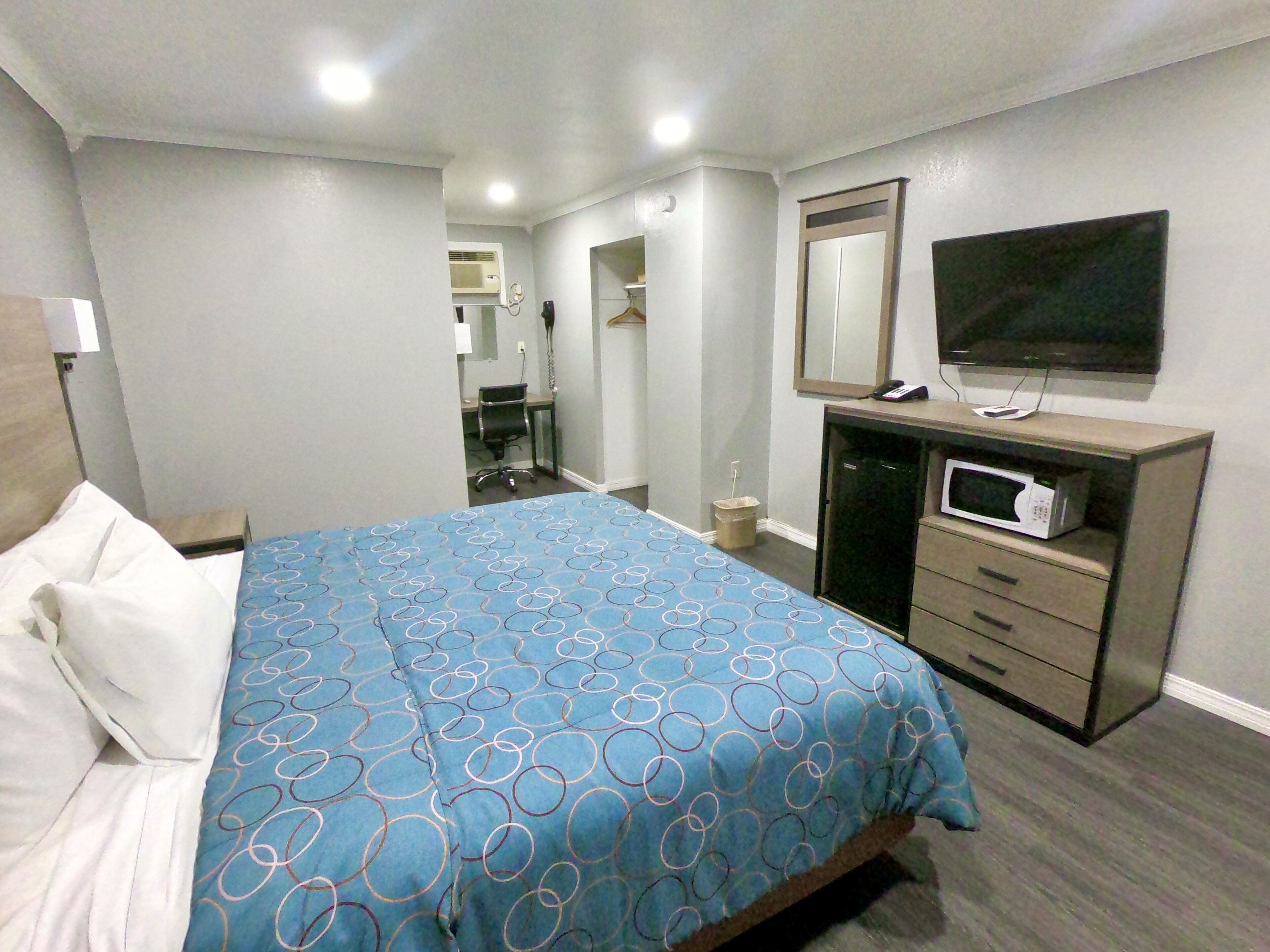 A hotel room with a bed, a desk, a television, and a microwave.
