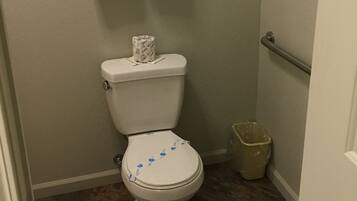 A small bathroom with a toilet, a trash can, and a towel rack with two white towels.