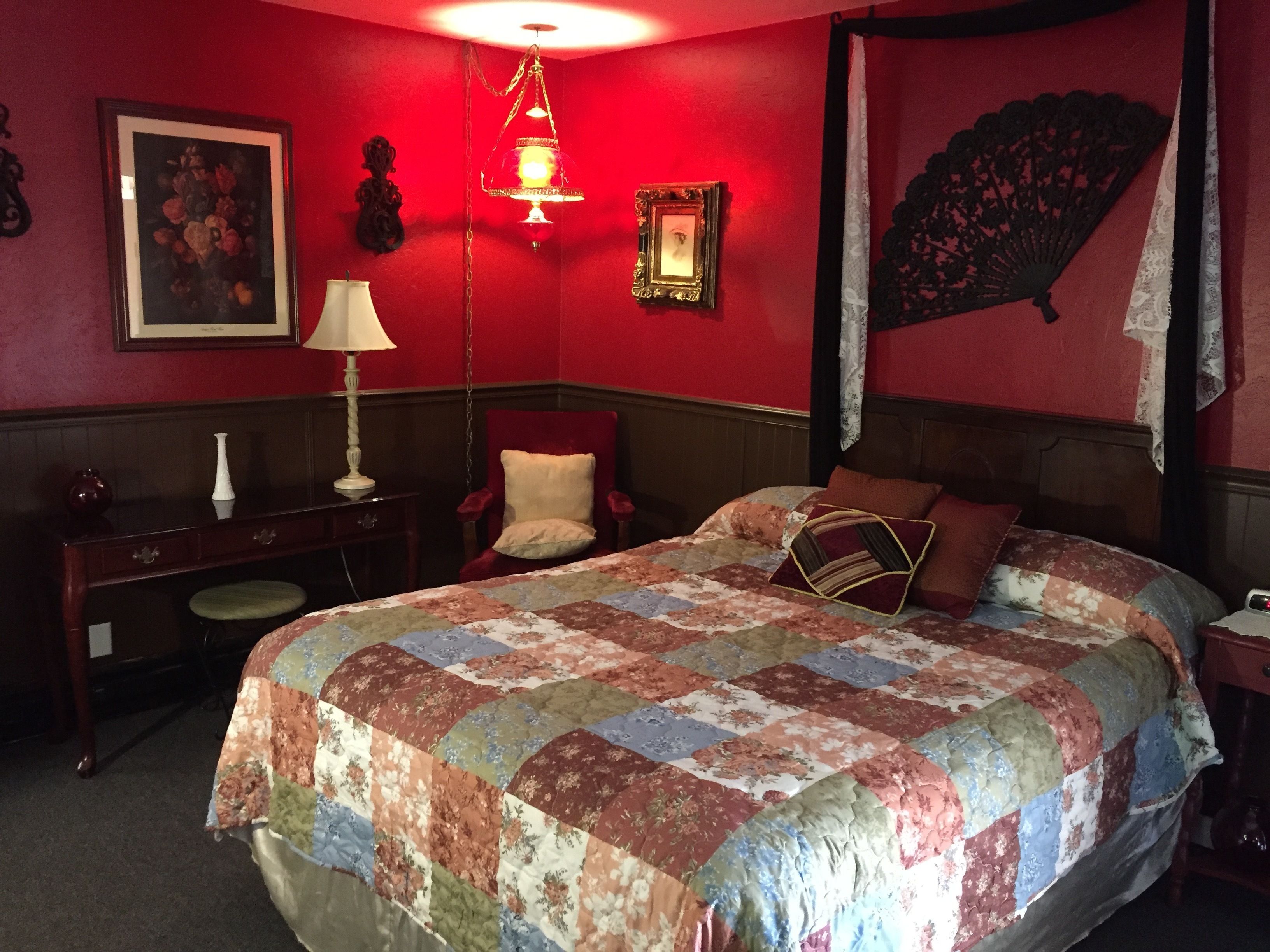 Una habitación con una cama grande, un escritorio, una silla y una lámpara.