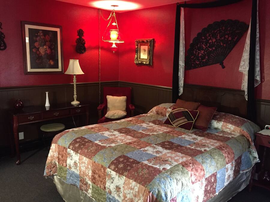 Una habitación con una cama grande, un escritorio, una silla y una lámpara.