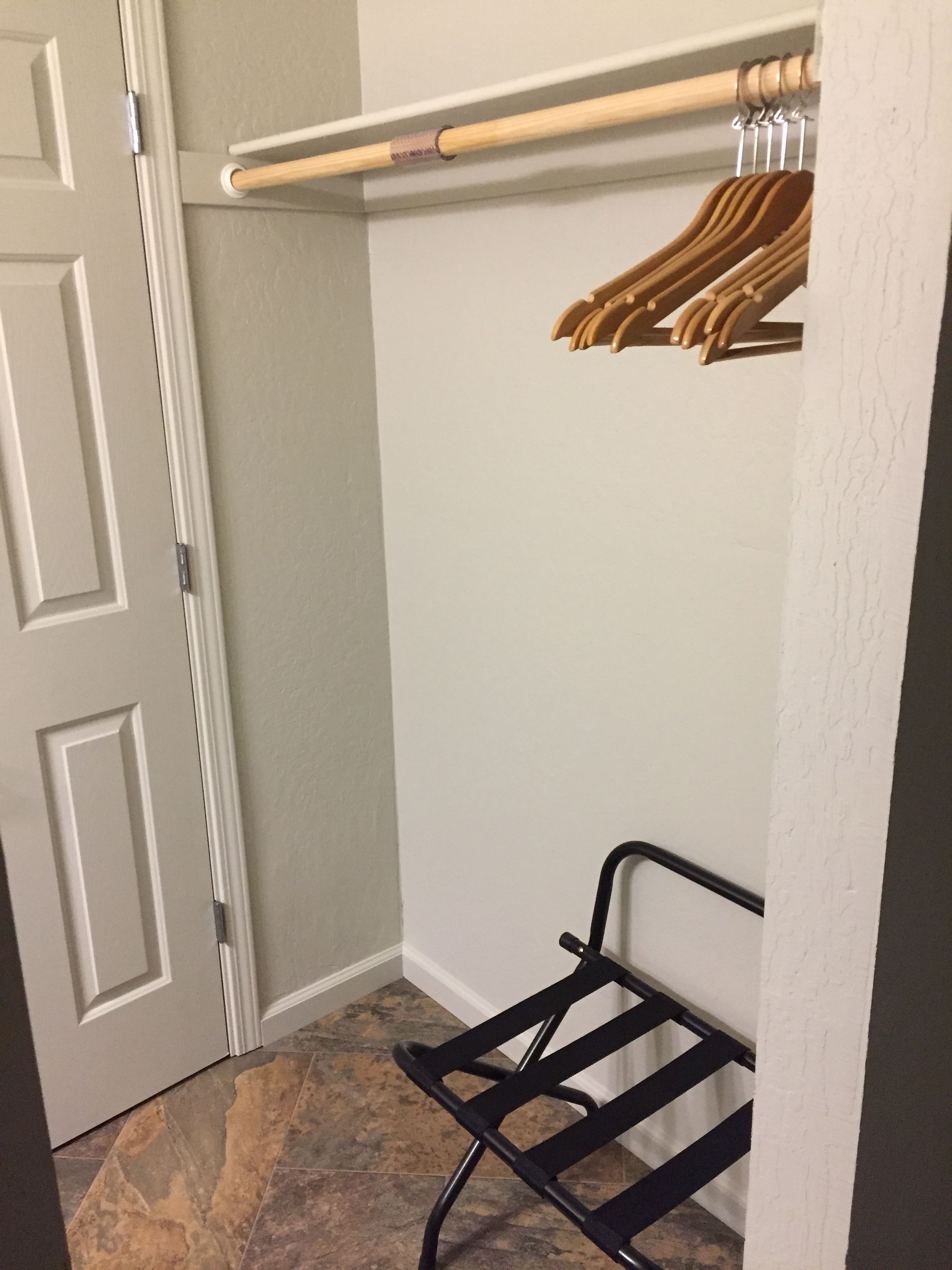 A corner of a room with a white door, a wooden coat rack, and a black metal shelf unit.