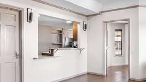 A hallway with a kitchen area, a door, and a window with blinds. - Rodeway Inn Waco Downtown near University (Waco)