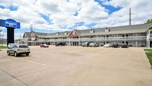 A motel with a signboard, multiple parking spaces, and a row of rooms with a covered walkway. - Rodeway Inn Waco Downtown near University (Waco)