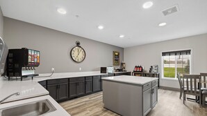 Une cuisine moderne dotée d’un îlot central, d’un four à micro-ondes encastré et d’une horloge murale.