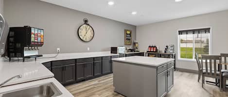 A modern kitchen with a central island, a built-in microwave, and a clock on the wall.