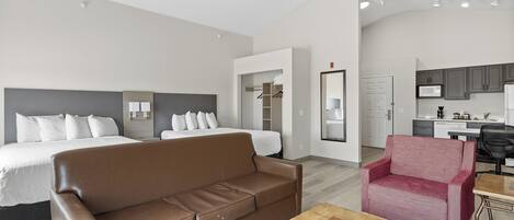 Una habitación de hotel moderna con una cama, un sofá marrón, un sillón rojo y una mesa de comedor.