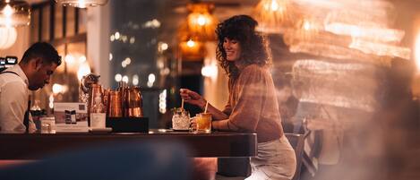 A bar area with a counter, stools, and hanging lights.