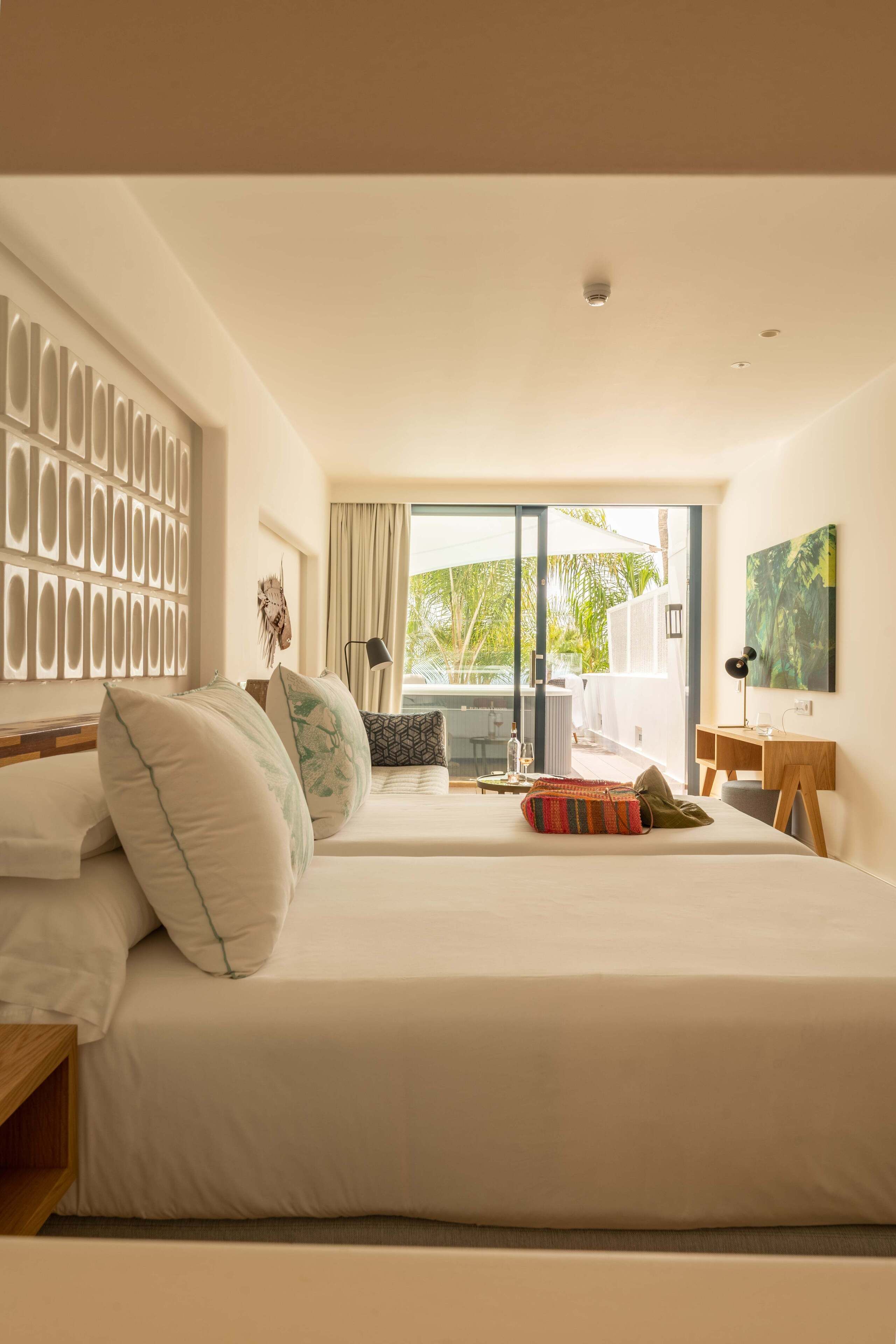 Une chambre d’hôtel moderne dotée d’un grand lit, d’un bureau et offrant une vue sur une piscine et un espace extérieur.