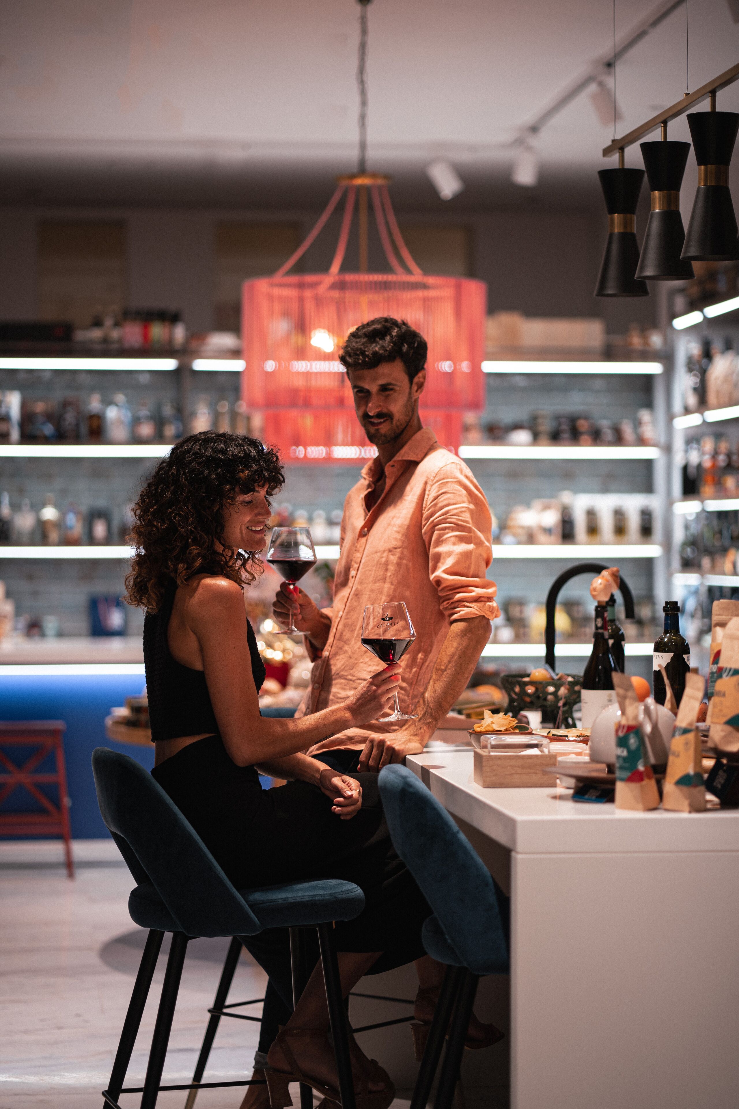 A couple seated at a bar with a wine bottle and glass on the counter.