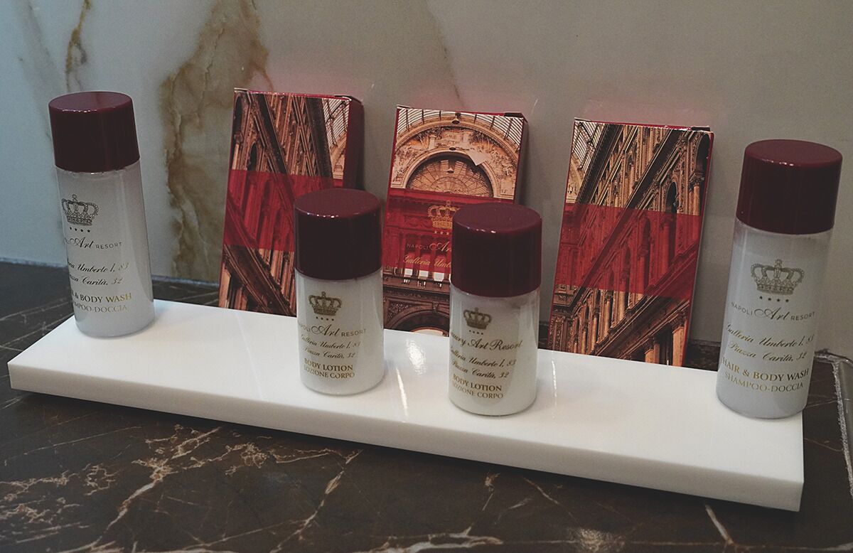 Una exhibición de botellas de jabón de baño y cuadros en una encimera de mármol.