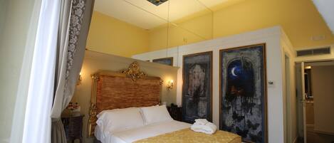Une chambre à coucher avec un grand lit, une table de chevet, une commode et deux grandes peintures au mur.