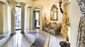 A grand lobby with marble flooring, a large ornate mirror, a golden statue, and a plush sofa. - Hotel Art Resort Galleria Umberto (Naples)