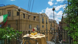 A table set outdoors with a yellow tablecloth, surrounded by a wrought iron fence, with buildings in the background. - Hotel Art Resort Galleria Umberto (Naples)
