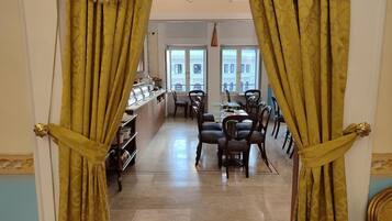 Angolo ristoro con buffet, sedie e vista sugli edifici attraverso ampie finestre.