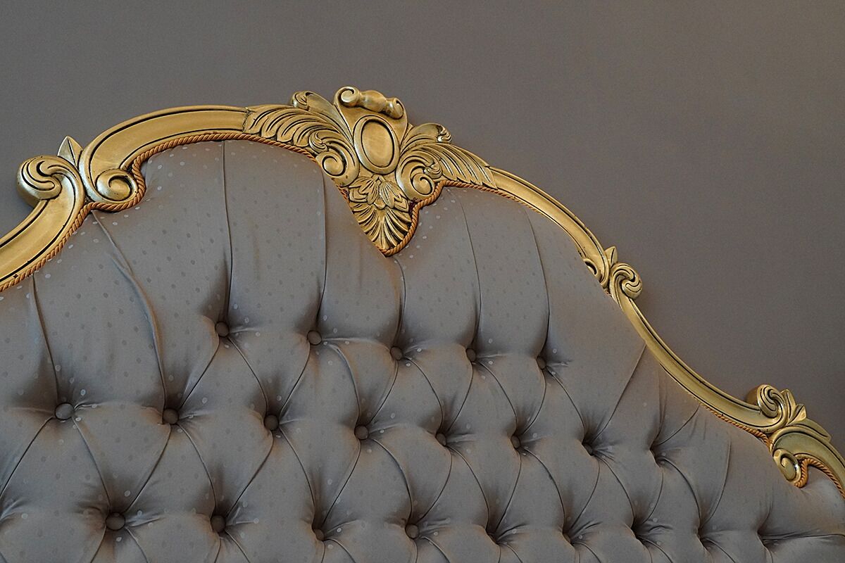 A tufted headboard with ornate gold detailing.