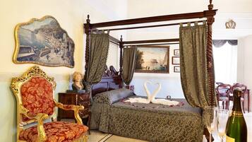 Un letto a baldacchino con tenda, una poltrona rivestita di fiori e un quadro appeso al muro.