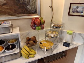 Een ontbijtbuffet met fruit, granen en een hoekje voor melklatte.