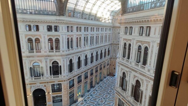 A grand interior with ornate architecture, a central open space, and a patterned floor. - Hotel Art Resort Galleria Umberto (Naples)