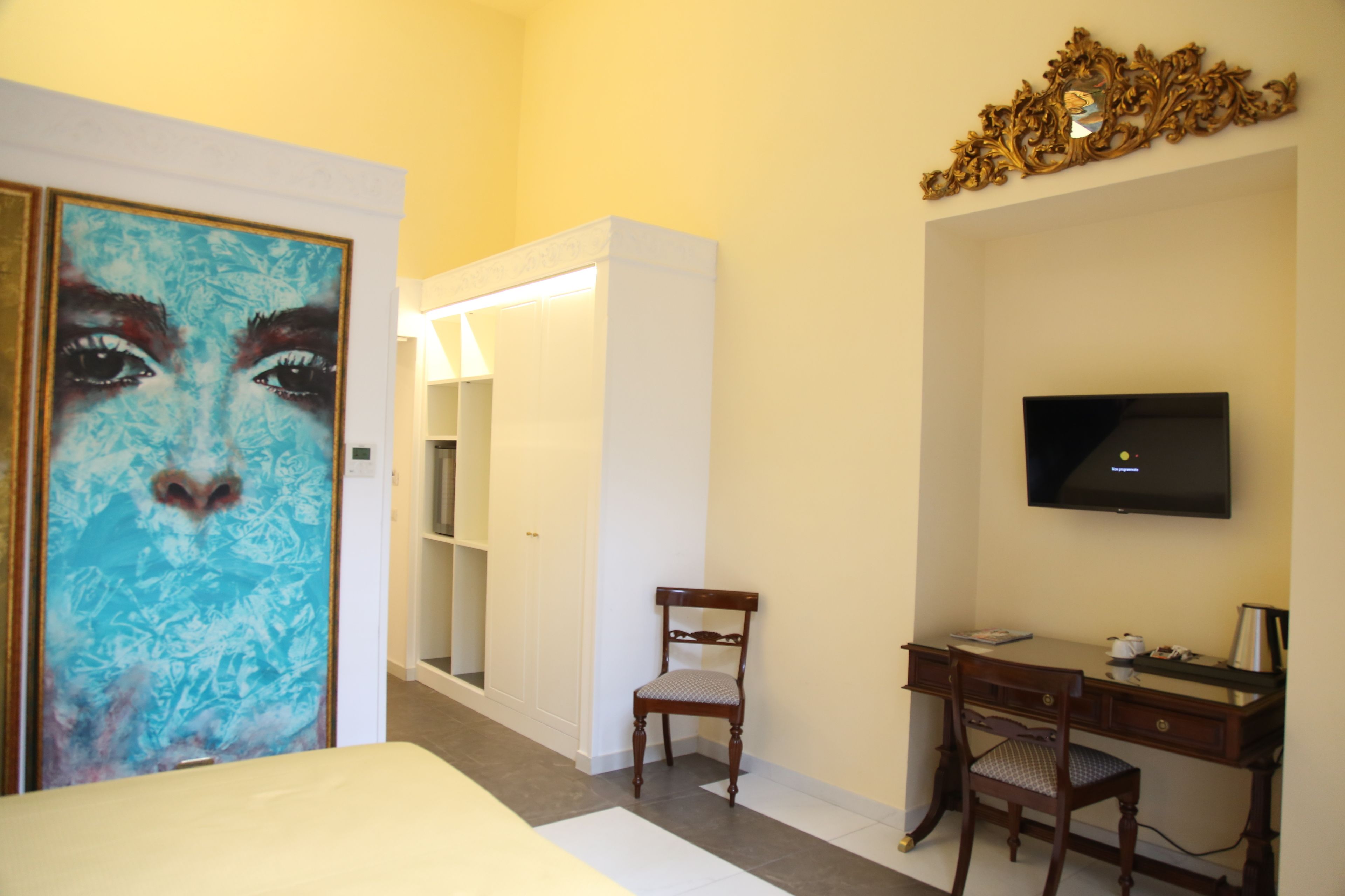 A hotel room with a bed, a desk, a chair, a television, and a wardrobe.