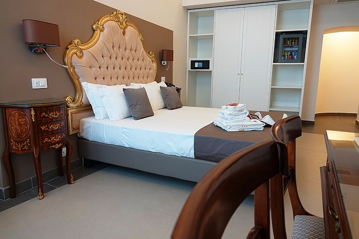 Una habitación de hotel con una cama grande, un armario, un escritorio y una silla.
