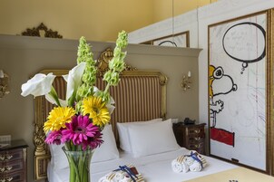 Een hotelkamer met een bed, een bloemenvaas en een muur met tekeningen.