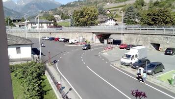 A road with vehicles, a pedestrian crossing, and a stone bridge.