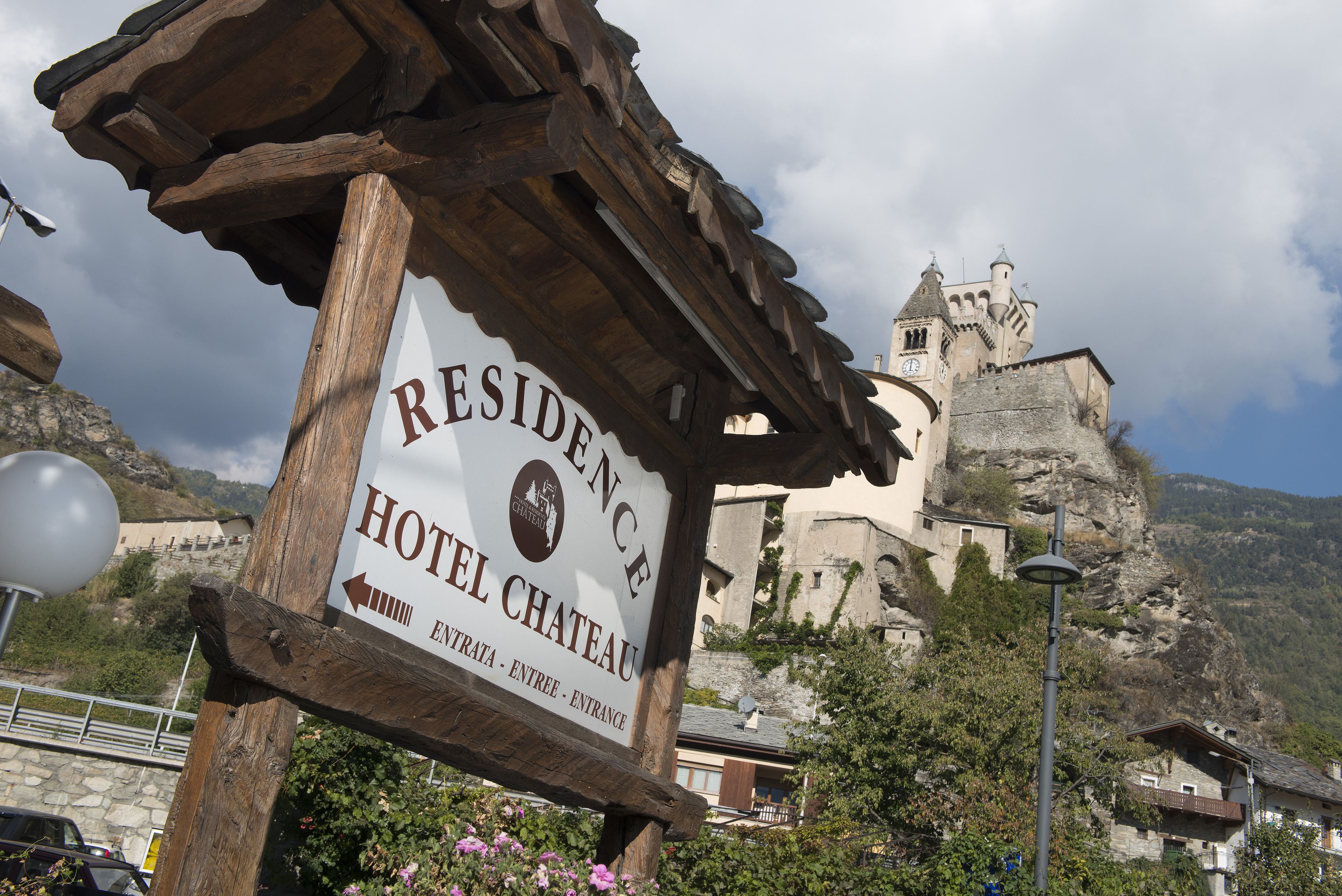 Schild für das Residence Hotel Chateau, im Hintergrund ein schlossähnliches Gebäude zu sehen.