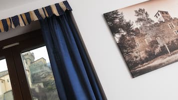 Una habitación con ventana, cortina e imagen colgada en la pared de un edificio.