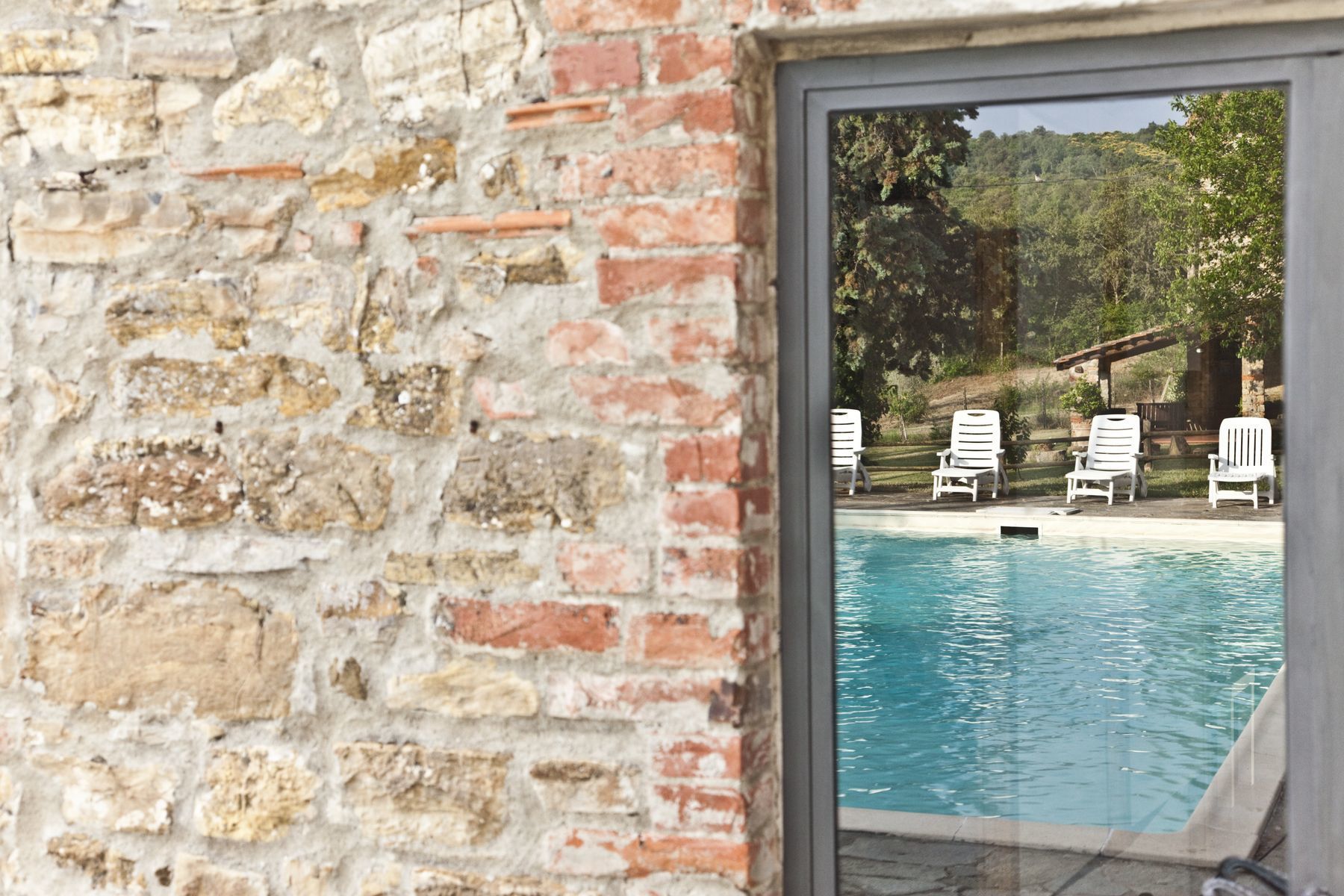 Blick auf einen Pool mit einer Ziegelwand und einer Glastür.
