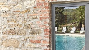 A poolside view with a brick wall and a glass door.