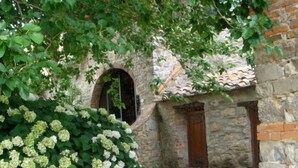 A stone building with a tiled roof, a wooden door, and a small arched window.