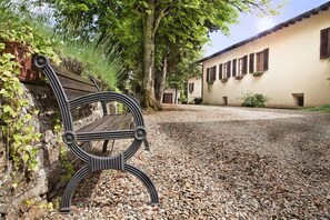 A bench with a metal frame, a gravel path, and a building with windows and plants.