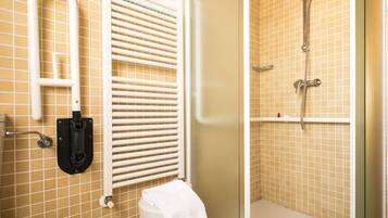 Un baño con ducha, inodoro y barra de apoyo.