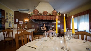 Een restaurant met houten stoelen, gedekte tafels en een bakstenen muur met decoratieve borden.