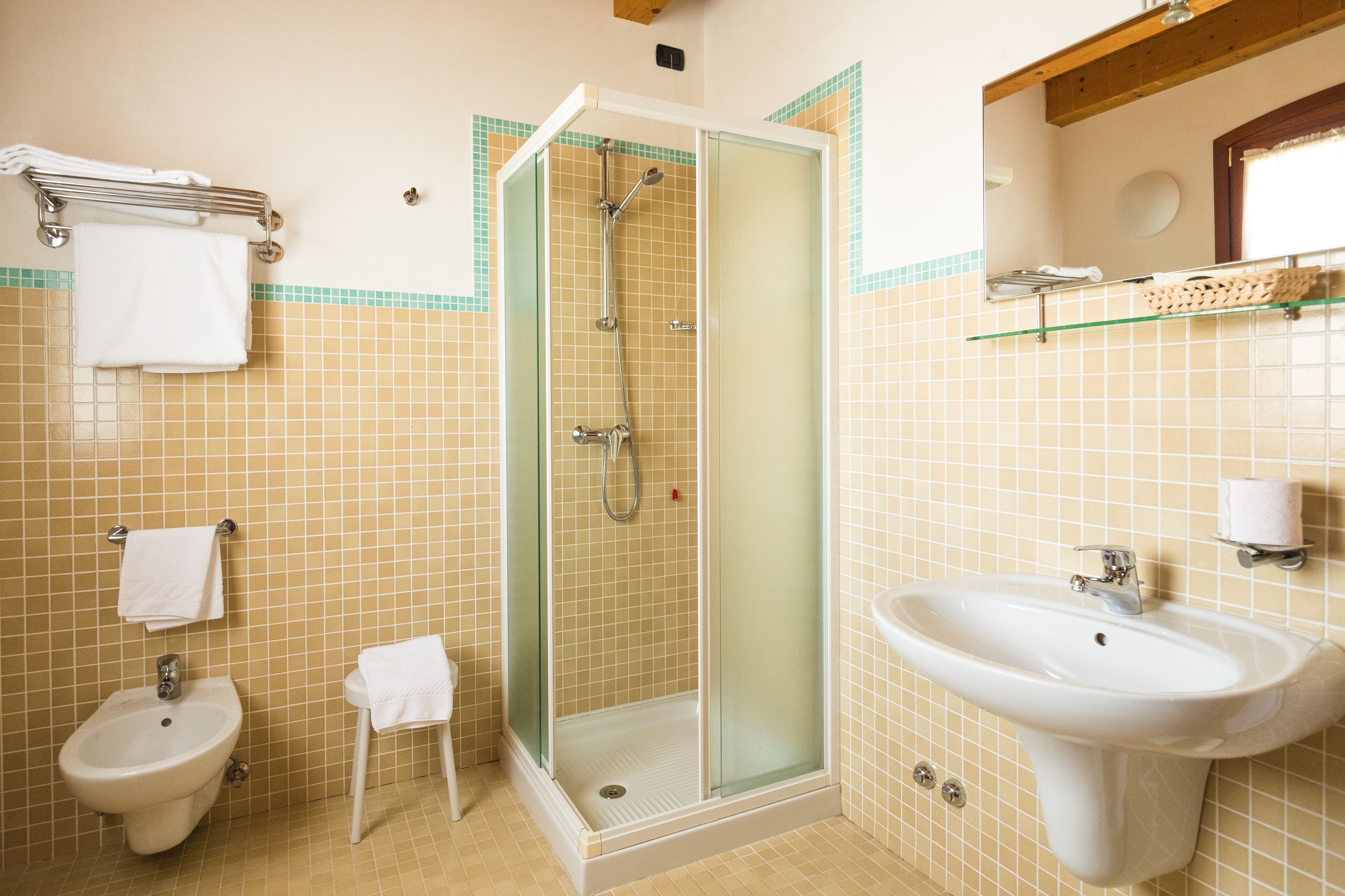 Un baño con ducha de vidrio, lavamanos pedestal y bidé.