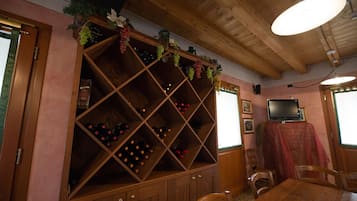 A room with a wooden wine rack, a dining table, chairs, and a television on a table.