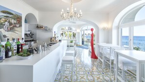 Uma cozinha moderna com área de bar, mobiliário branco e vista para o mar.